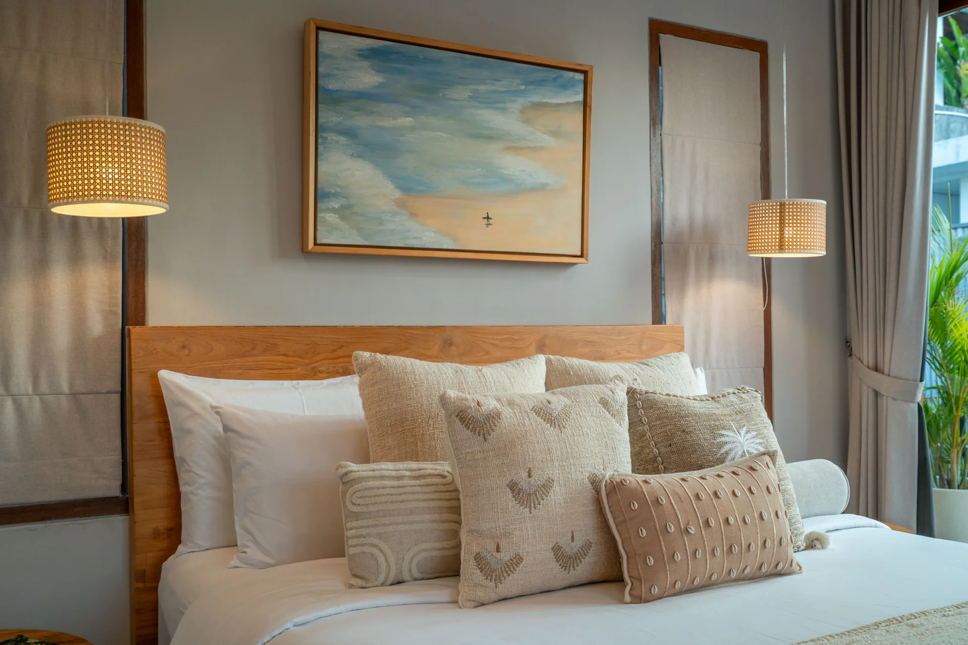 Master bedroom styling - neutral linens, original artwork, rattan pendant lighting