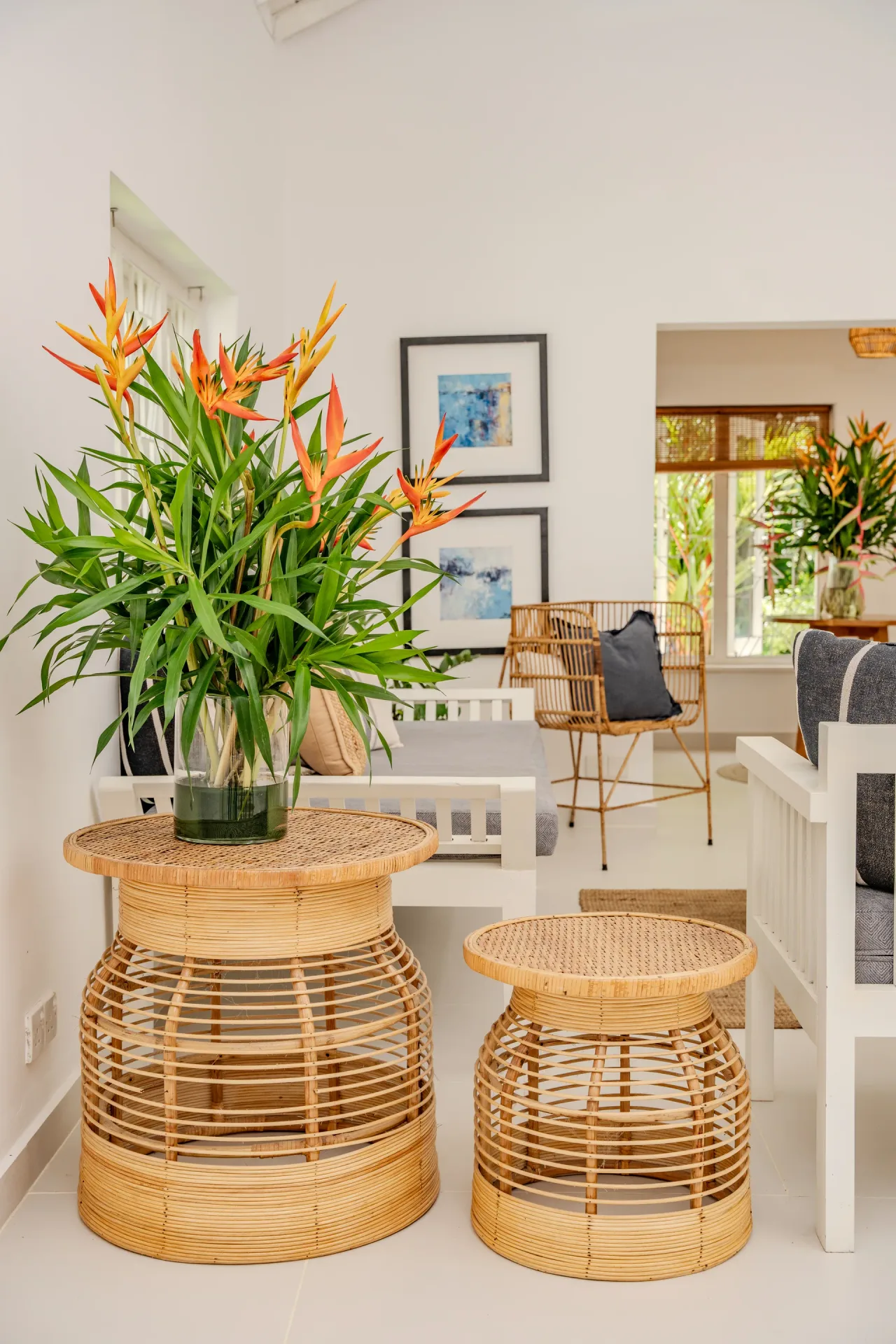 Rattan side tables with heliconia flowers and abstract artwork